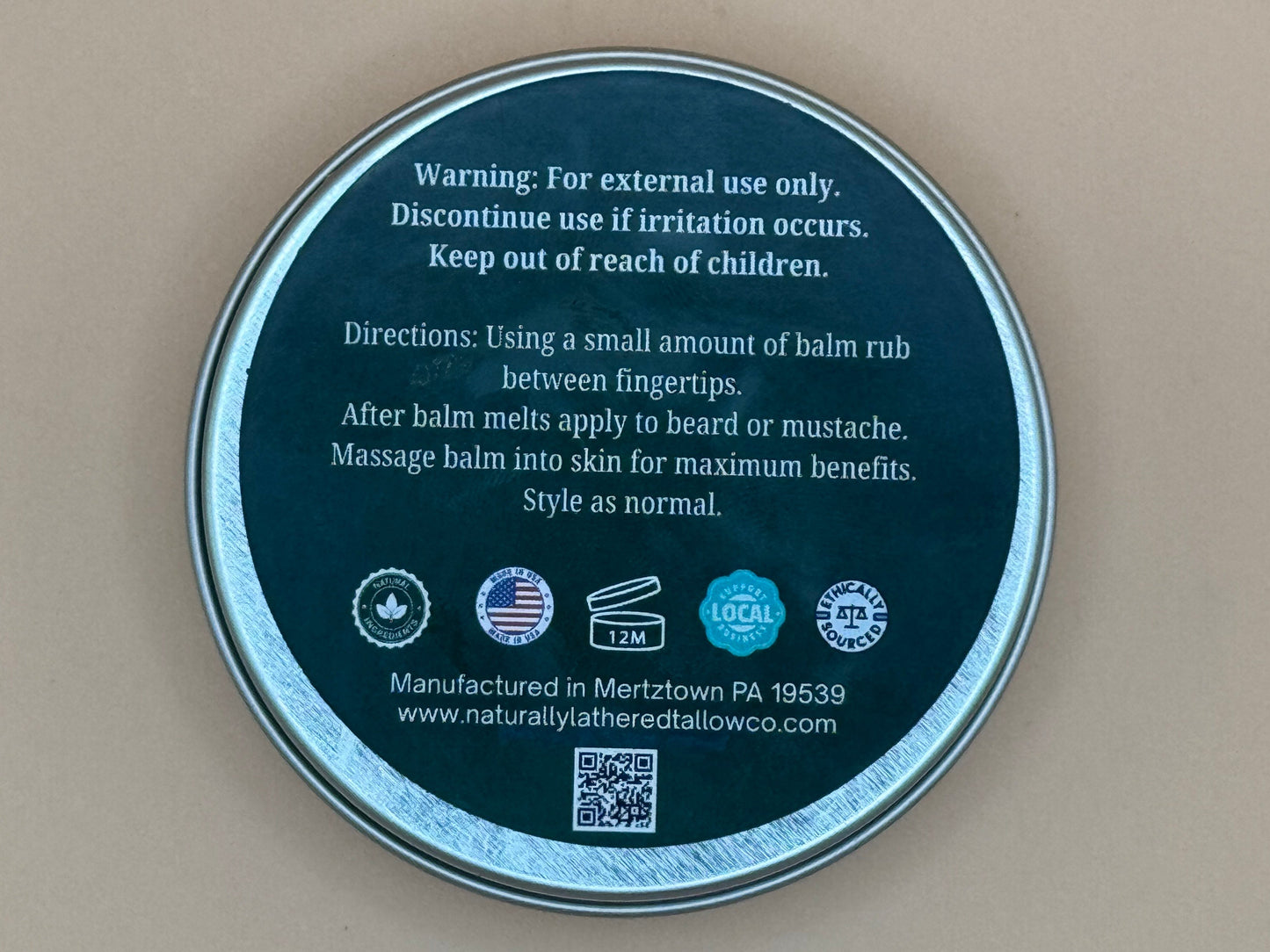 Round metal container lid with text and logos on a beige background