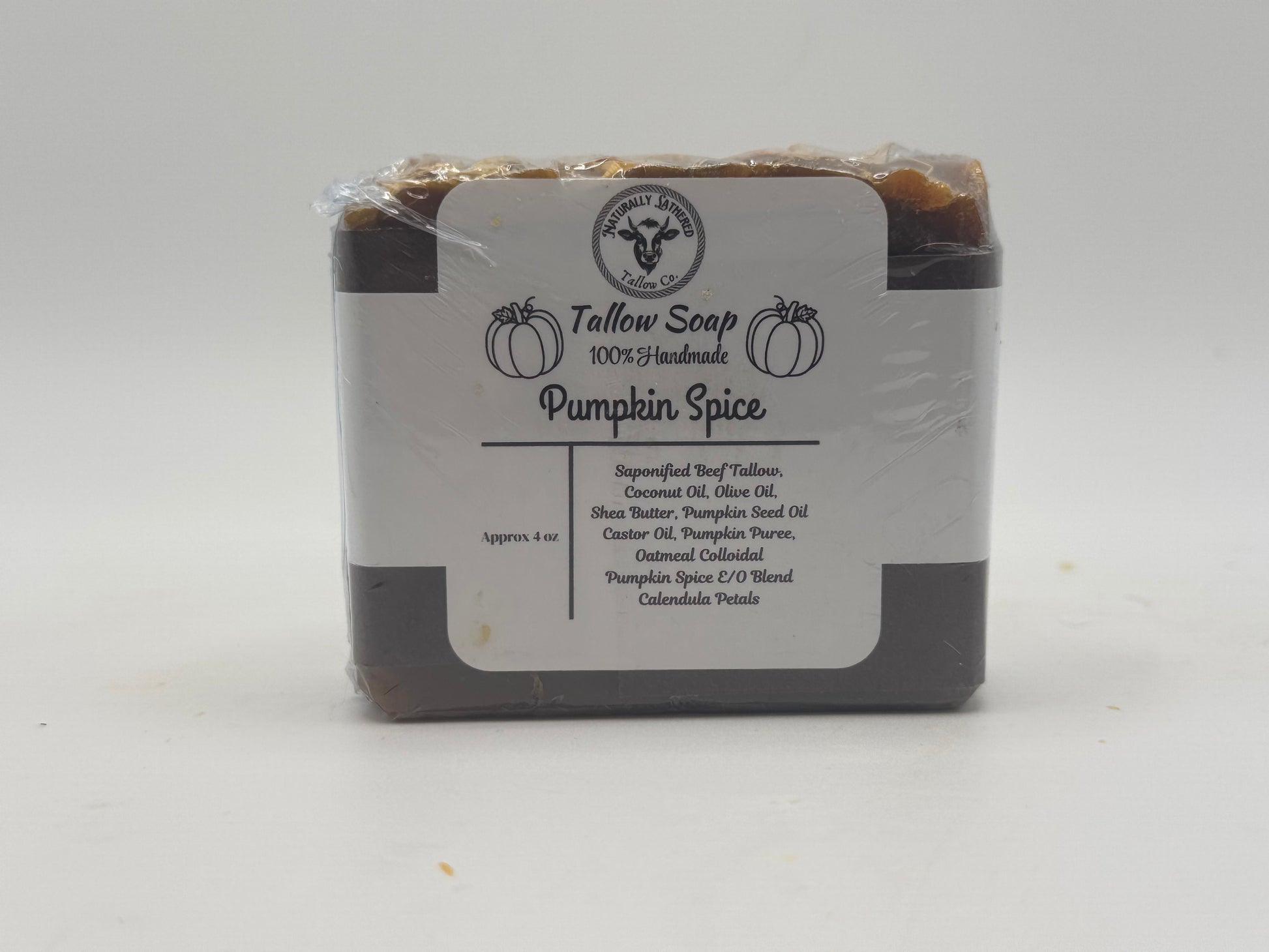 Pumpkin spice soap bar wrapped in clear plastic with a label on a white background