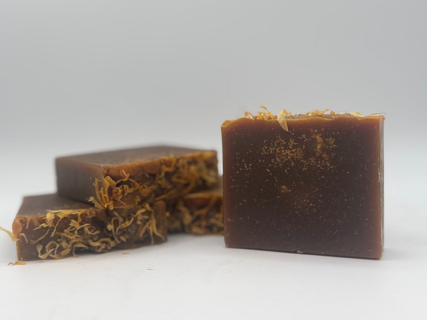 Three brown soap bars with specks on a white background