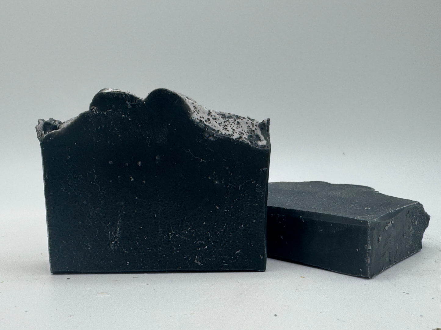 Two bars of black soap on a light gray background