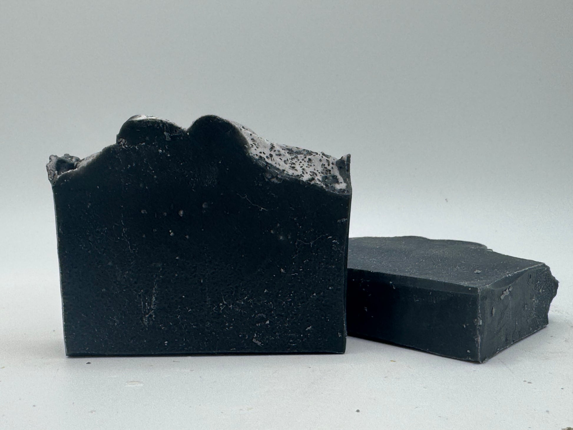Two bars of black soap on a light gray background