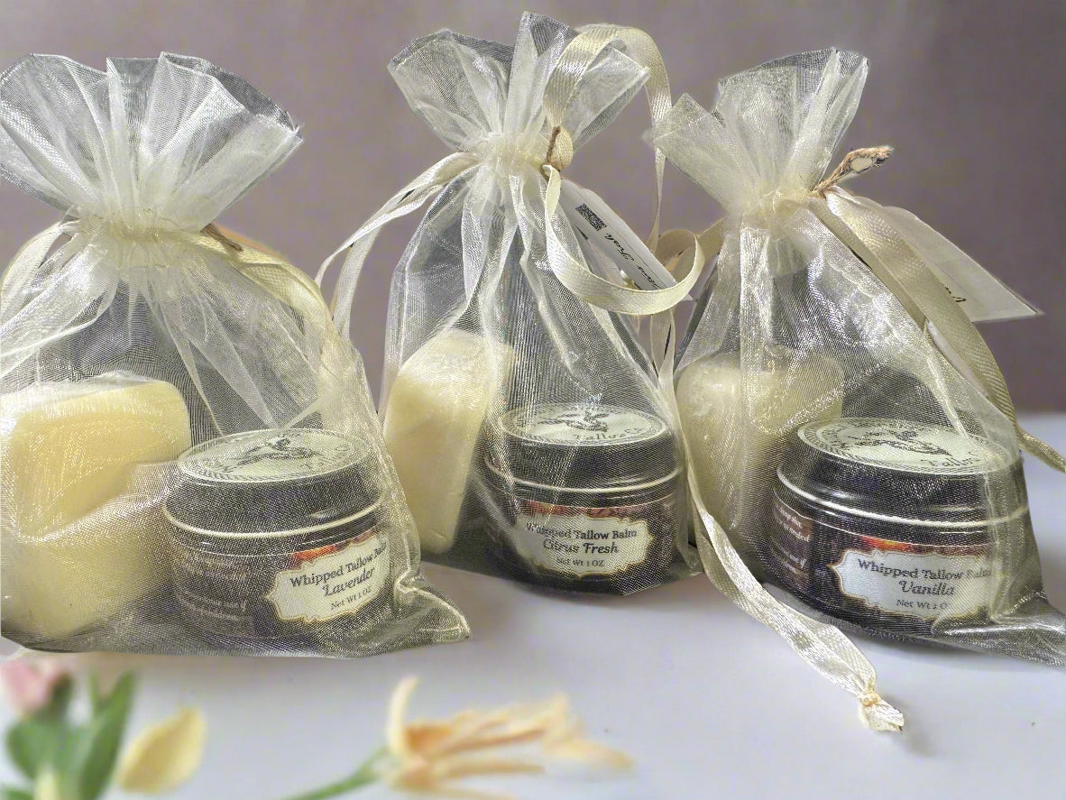 The image displays several clear organza bags with drawstrings, each containing different items including a white bar of soap and jars of balm. They are tied with beige ribbons, presenting a neat and appealing appearance.