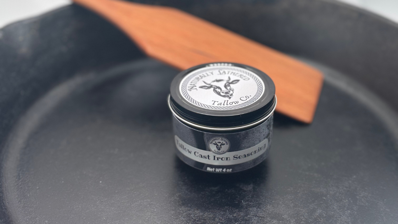 Small container of leather care product on a black leather surface with a wooden tool.