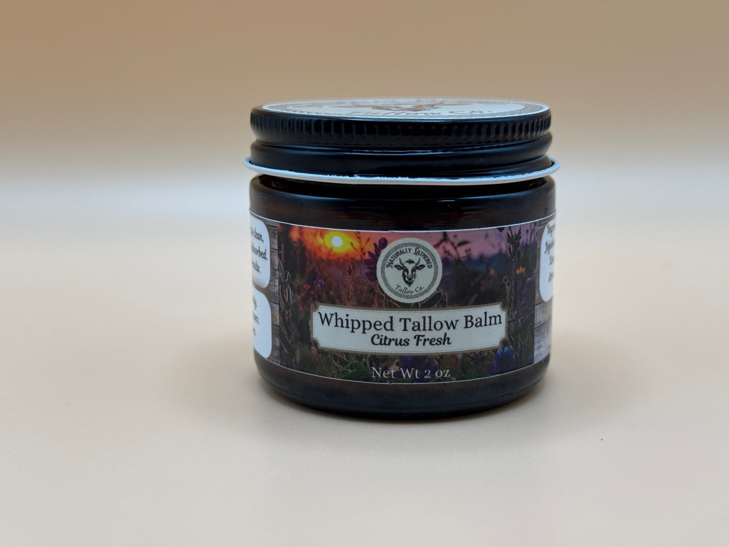 Jar of Whipped Tallow Balm with a label on a beige background