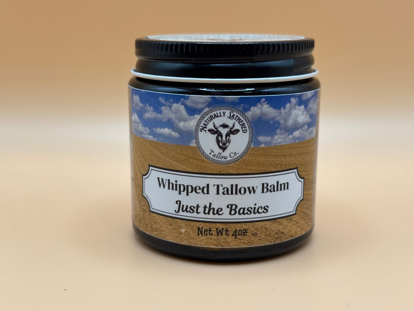 Jar of whipped tallow balm with a label on a beige background