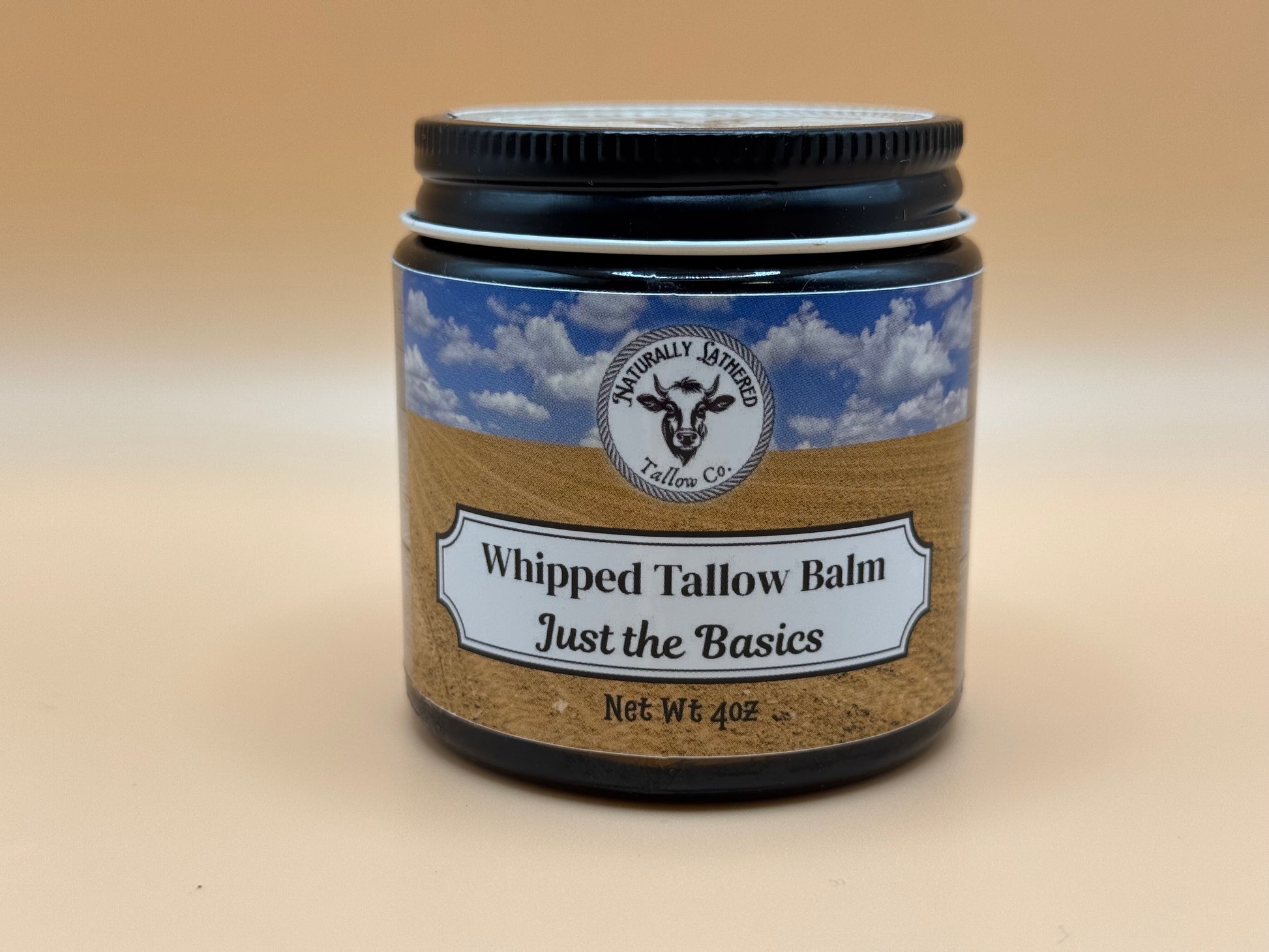 Jar of whipped tallow balm with a label on a beige background