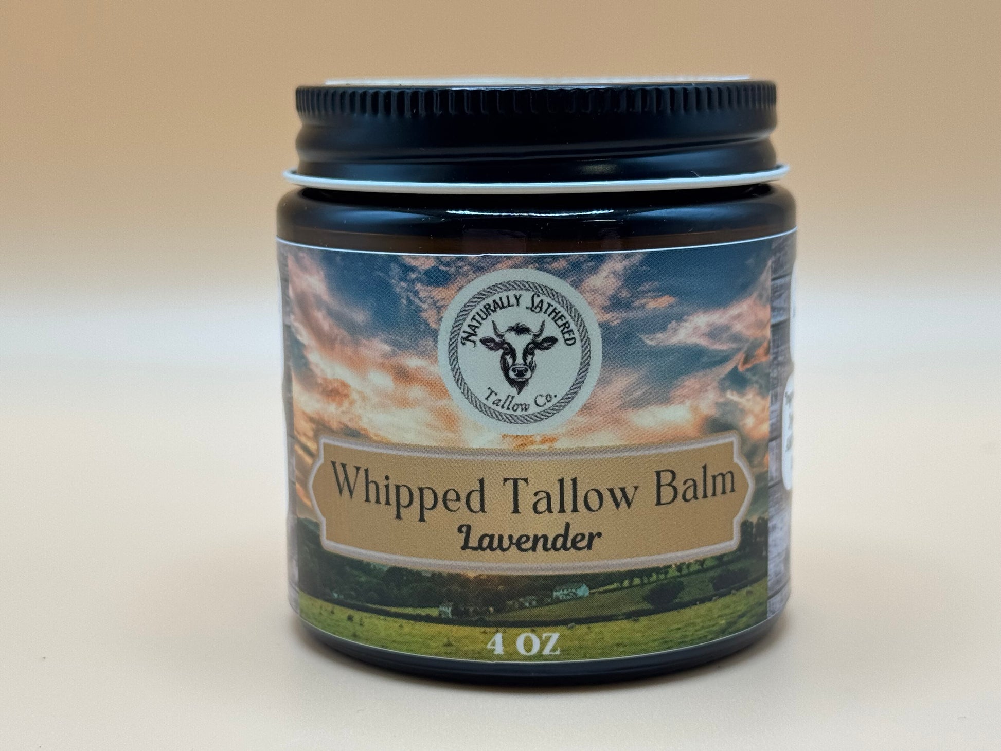 Jar of Whipped Tallow Balm Lavender with a scenic label on a beige background