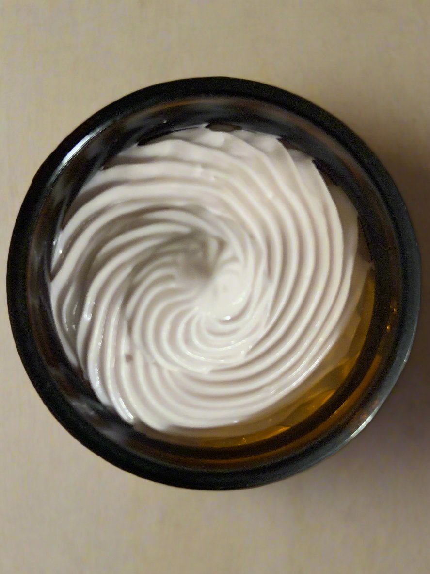 A jar of whipped magnesium balm with a white creamy texture visible through the clear glass.