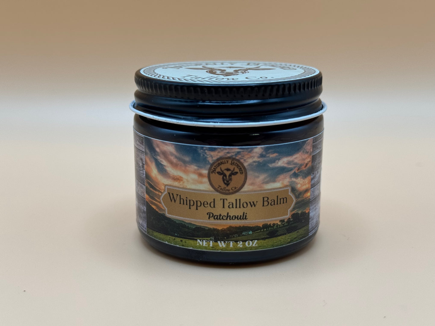 Jar of Whipped Tallow Balm with a label on a beige background